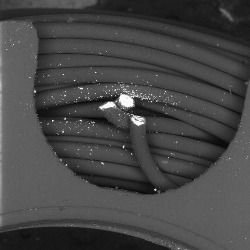 BSE SEM image of fractured magnet wire ends and copper debris in winding